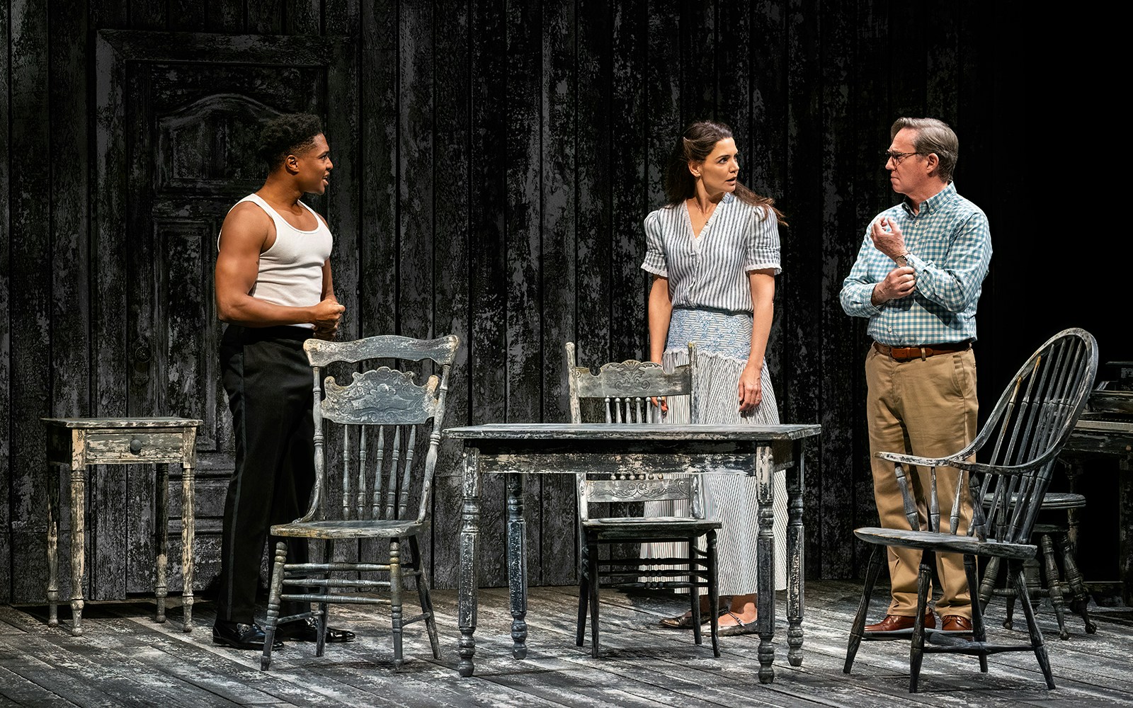 Three actors perform a scene from "Our Town" on a rustic stage set.