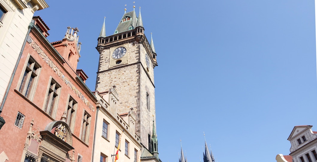 Old Town Hall Tower in Prague with clock and Gothic architecture against blue sky.