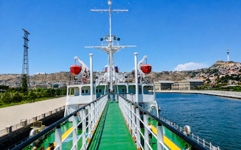 Deck view of the world's first tanker museum ship in Baku, with cityscape and Caspian Sea in the background.