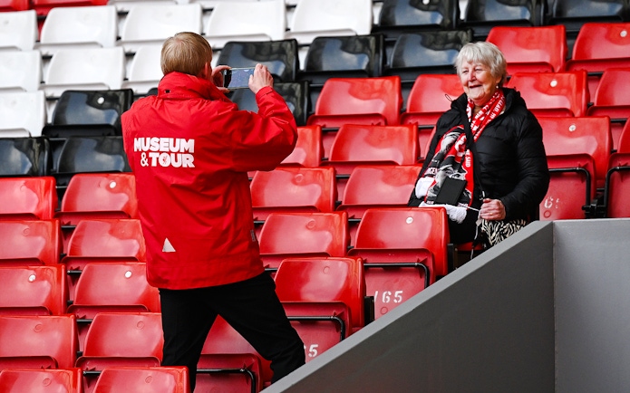 Tour guide photographing a visitor at Anfield Stadium in Liverpool.