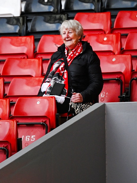 Tour guide photographing a visitor at Anfield Stadium in Liverpool.