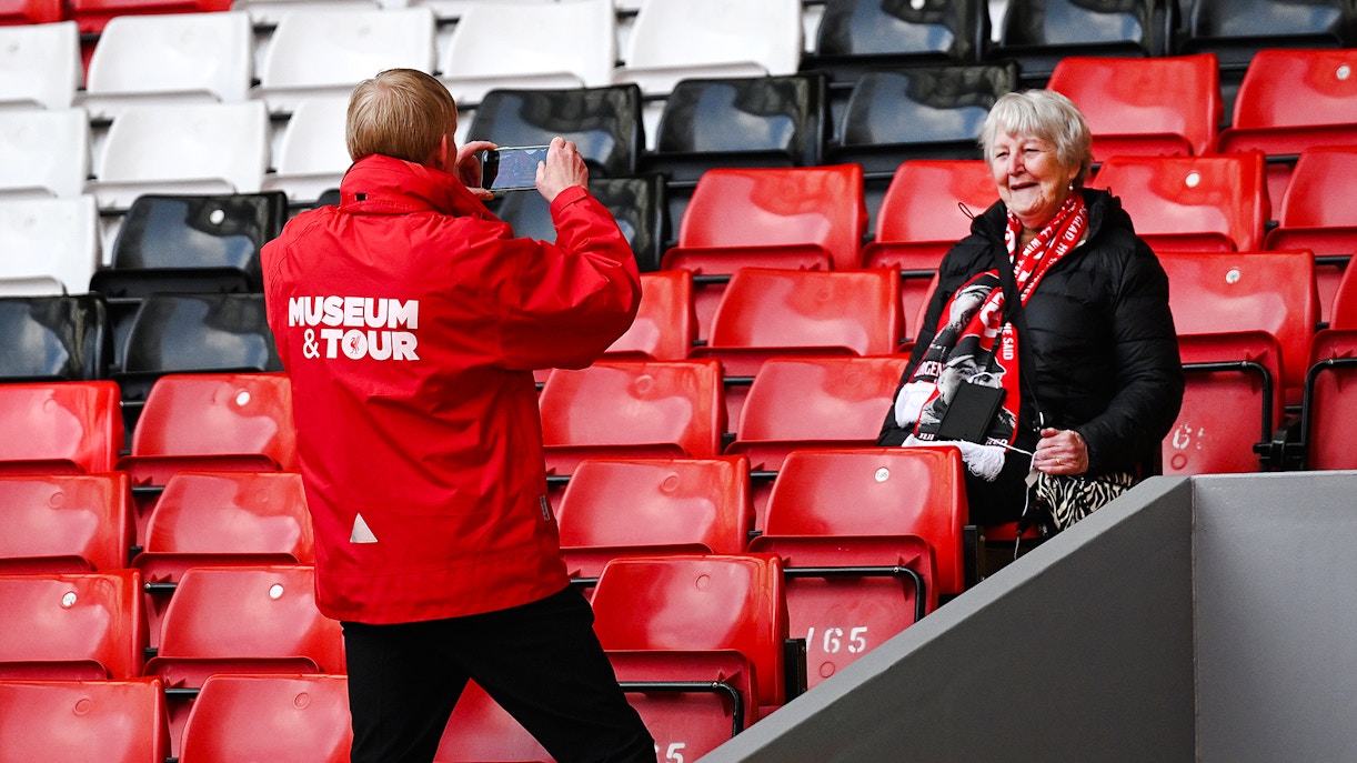 Tour guide photographing a visitor at Anfield Stadium in Liverpool.