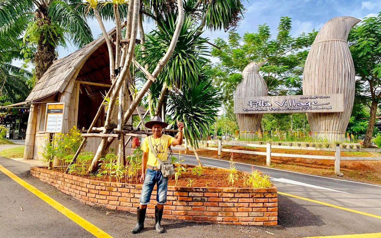 Entrance to Pita Village with a local guide standing near tropical plants.