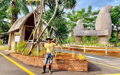 Entrance to Pita Village with a local guide standing near tropical plants.