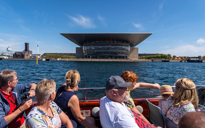 Tourists on a boat tour in Copenhagen viewing the Copenhagen Opera House.