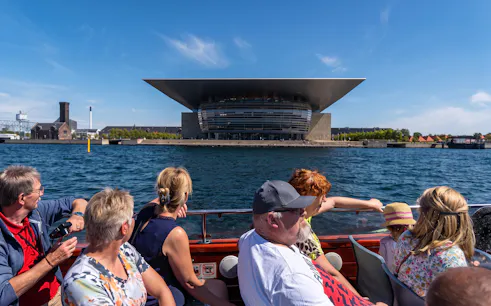 Tourists on a boat tour in Copenhagen viewing the Copenhagen Opera House.