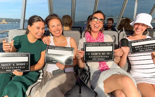 Group enjoying Sydney Harbour's True Crime Cruise with playful signs.