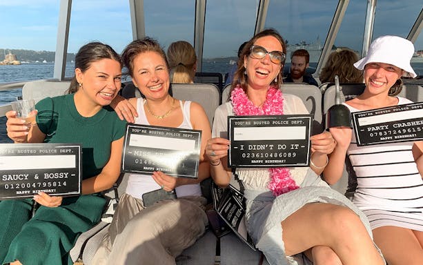 Group enjoying Sydney Harbour's True Crime Cruise with playful signs.
