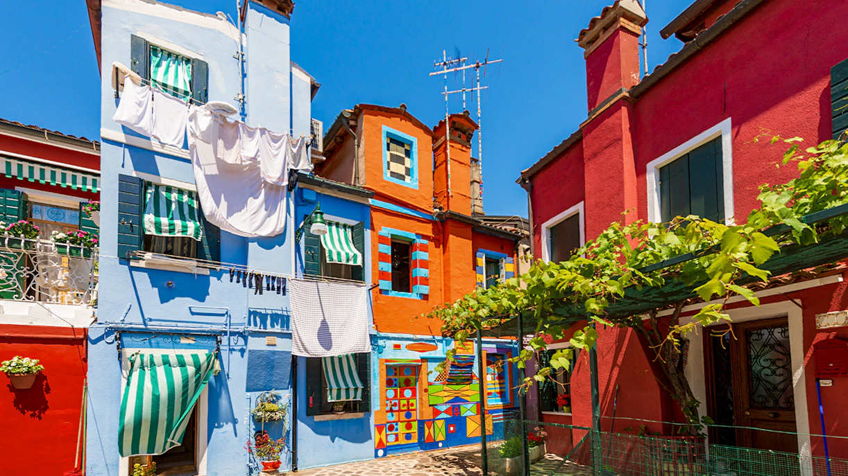 Colorful facade of Bepi's House in Burano, Venice, with vibrant patterns and striped awnings.