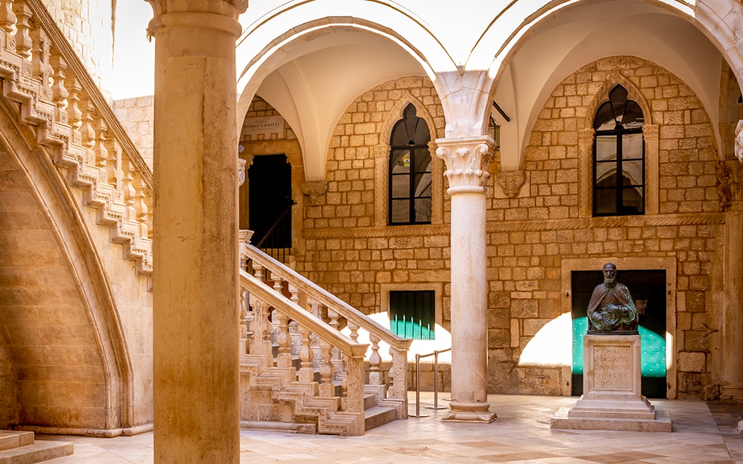 Rector's Palace courtyard with stone staircase and statue in Dubrovnik.