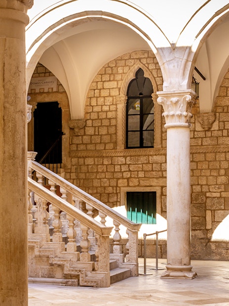 Rector's Palace courtyard with stone staircase and statue in Dubrovnik.