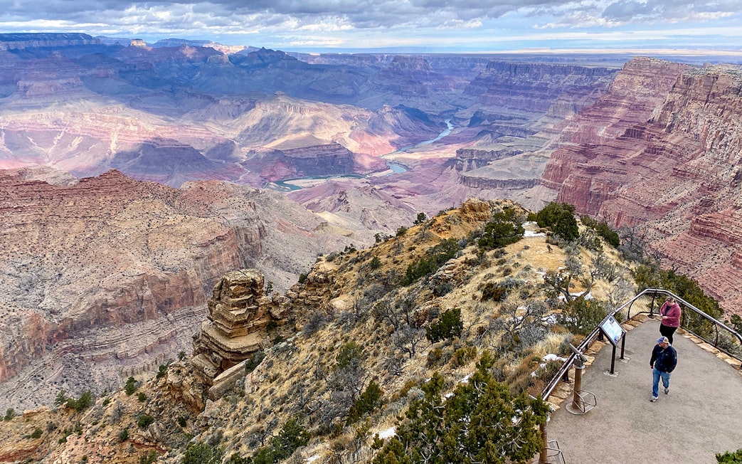 Grand Canyon South Rim overlook with visitors and expansive canyon view.
