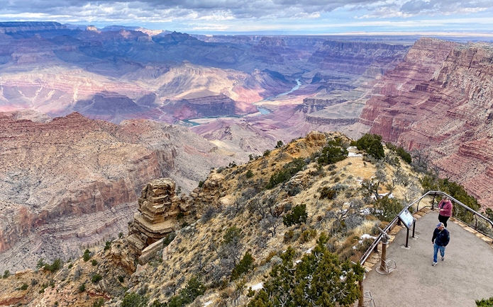 Grand Canyon South Rim overlook with visitors and expansive canyon view.