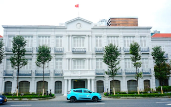 Historic colonial building with Vietnamese flag in Da Nang city tour.