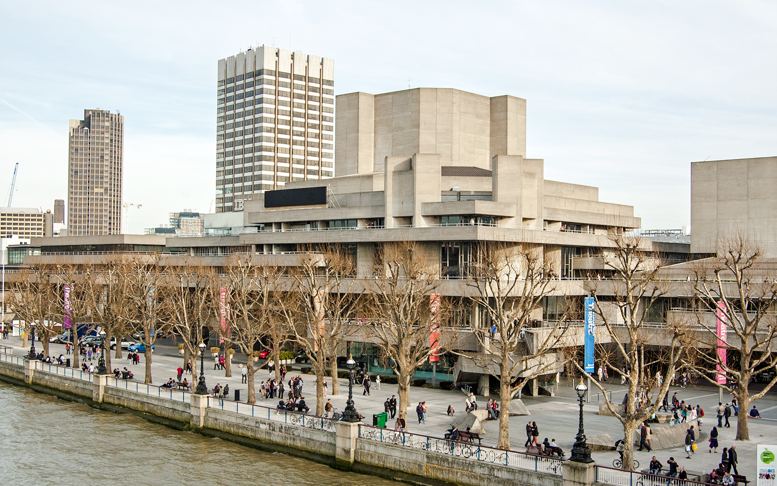 National Theatre on South Bank, London with people walking along the riverside.