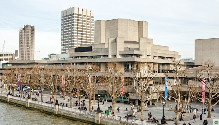 National Theatre on South Bank, London with people walking along the riverside.