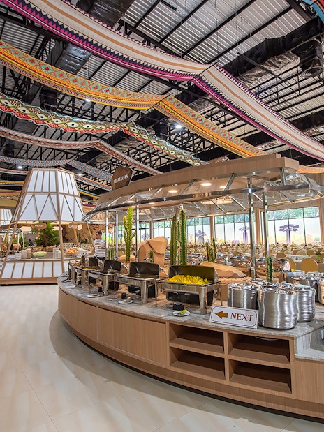 Buffet setup at Savanna restaurant in Safari World with colorful ceiling decor.