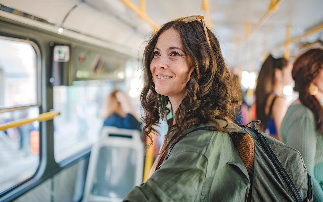 Traveller smiling on a bus, using public transport.