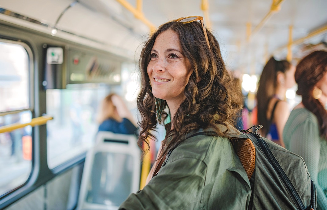 Traveller smiling on a bus, using public transport.