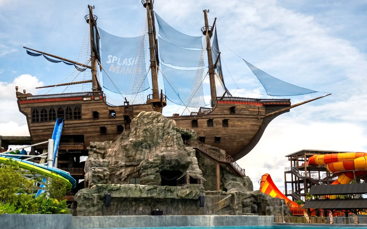 Pirate ship structure at SplashMania Waterpark, Kuala Lumpur, with water slides and rock formations.