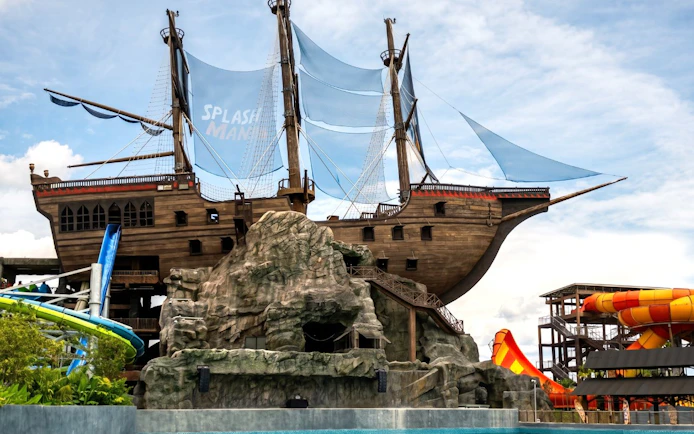 Pirate ship structure at SplashMania Waterpark, Kuala Lumpur, with water slides and rock formations.