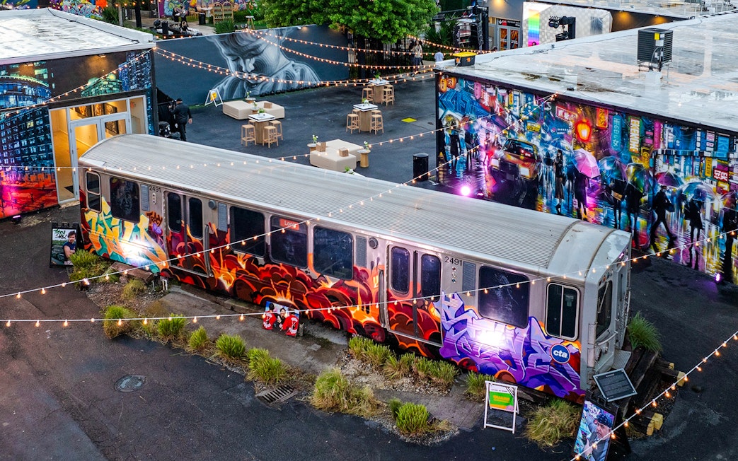 Graffiti-covered train car at Wynwood Walls Museum, Miami, surrounded by vibrant murals and string lights.
