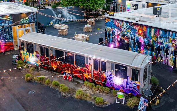 Graffiti-covered train car at Wynwood Walls Museum, Miami, surrounded by vibrant murals and string lights.