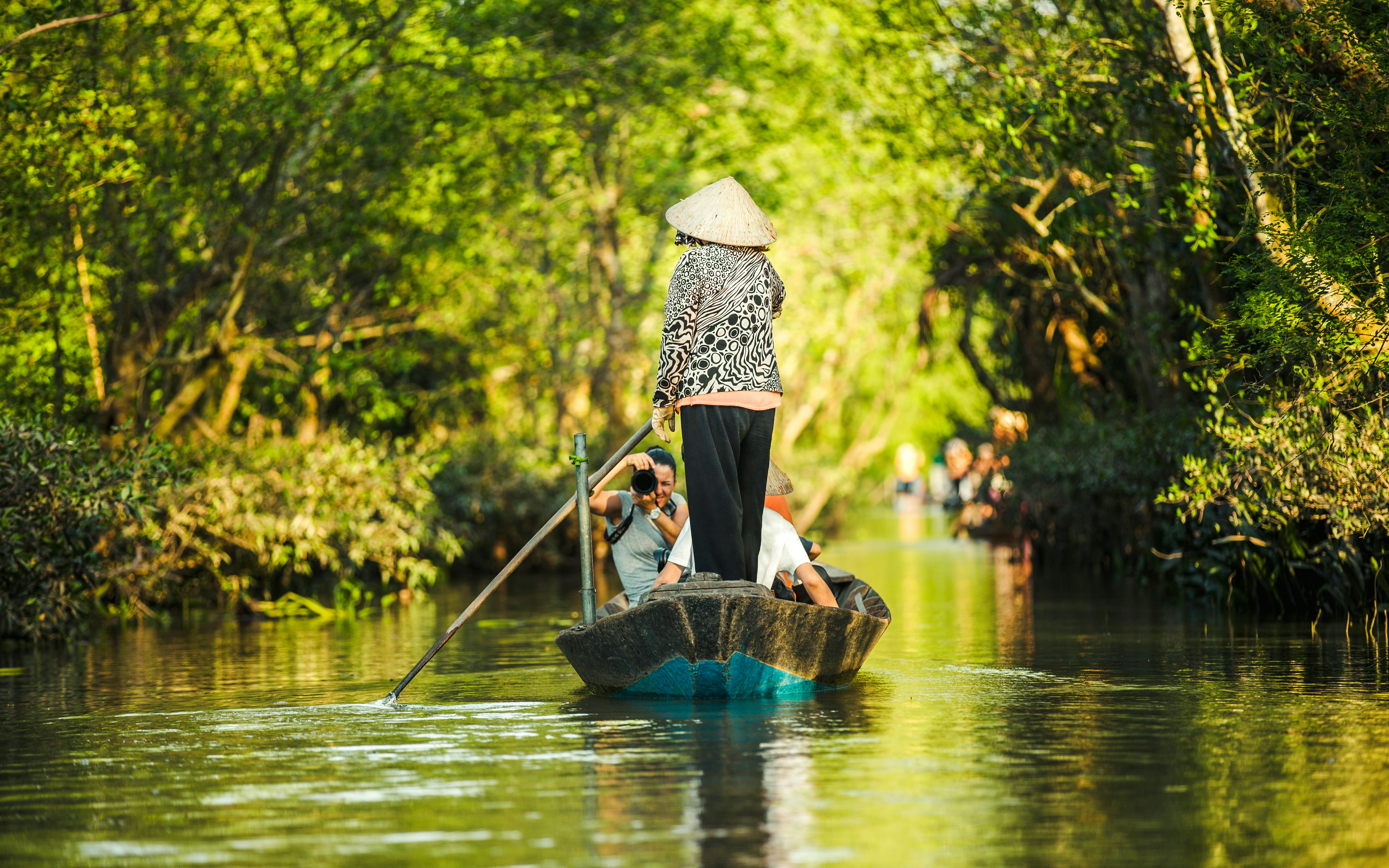 Tourists in a boat rowed by a woman on the Mekong River, My Tho, Vietnam