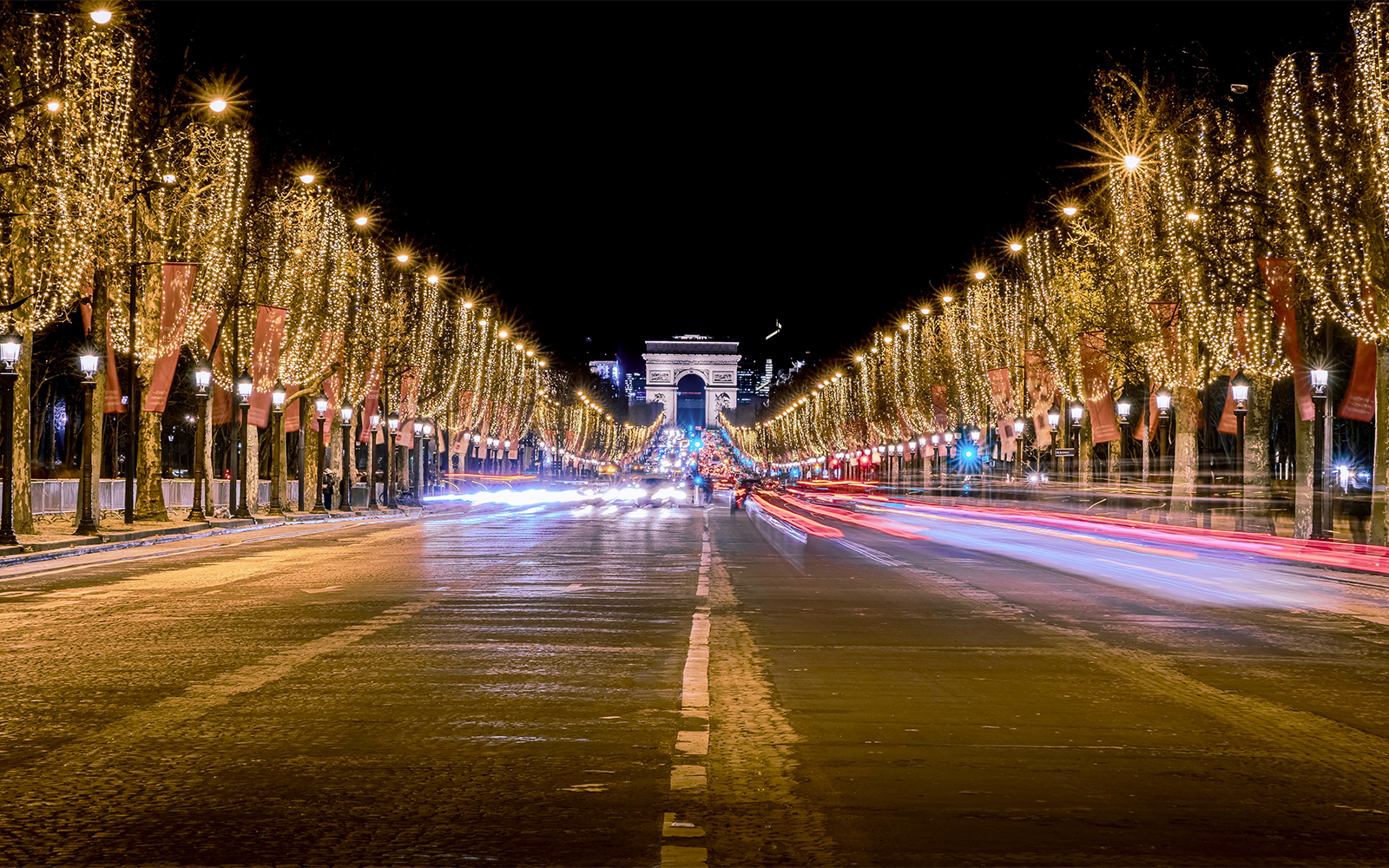 Champs-Élysées illuminated with Christmas lights, Arc de Triomphe in background, Paris Christmas light tour.