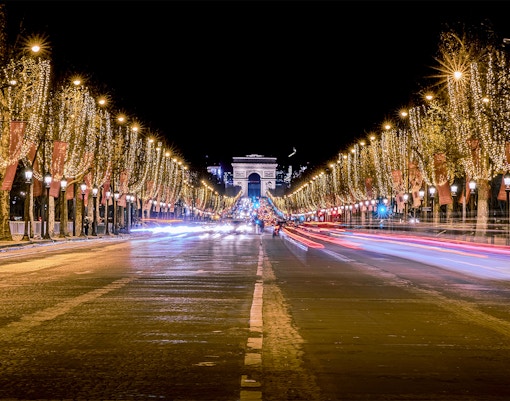 Champs-Élysées illuminated with Christmas lights, Arc de Triomphe in background, Paris Christmas light tour.