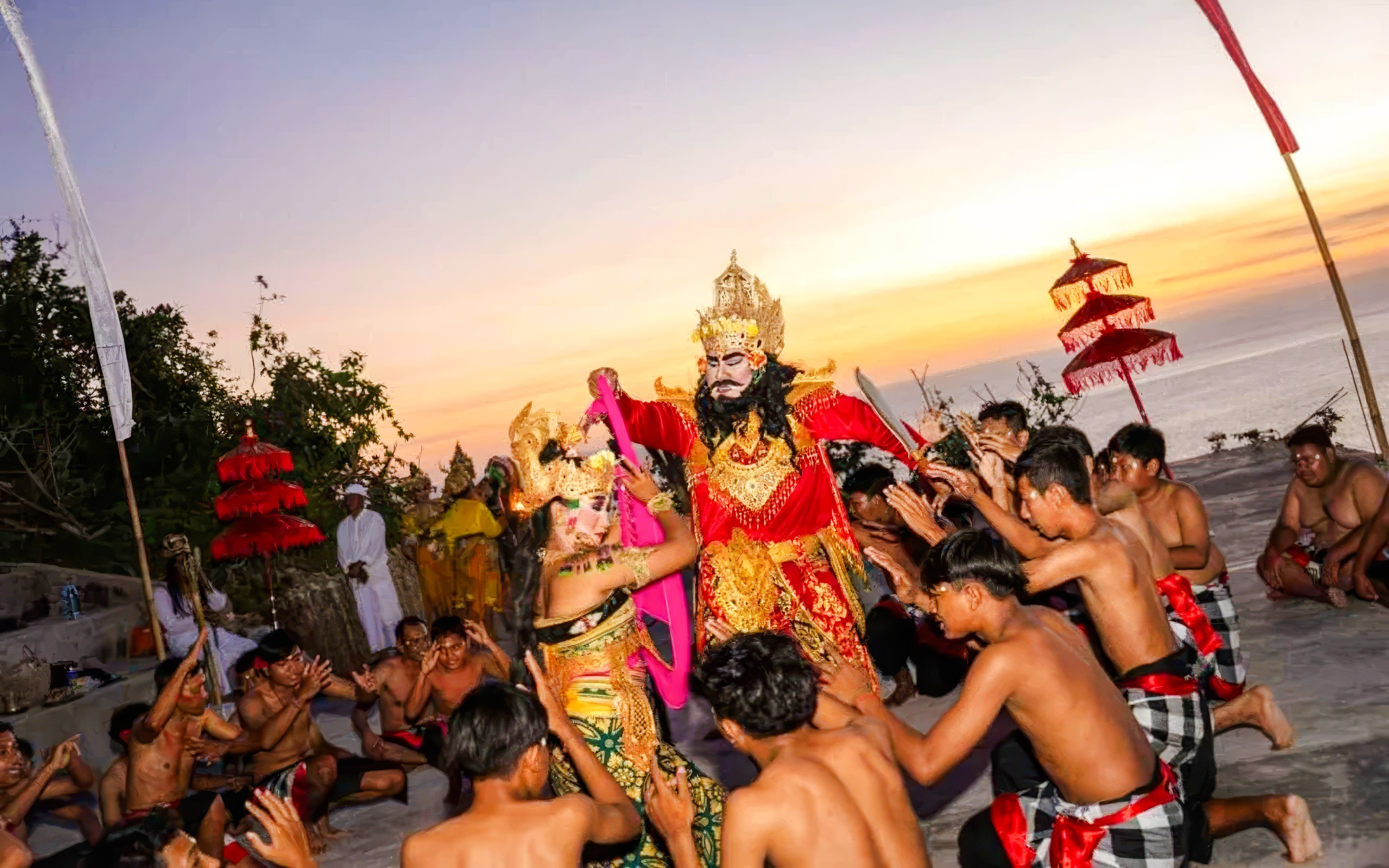 Kecak dance performance at Uluwatu Temple, Bali, with performers in traditional costumes at sunset.