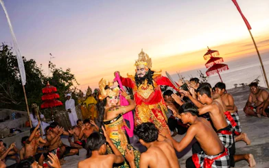 Kecak dance performance at Uluwatu Temple, Bali, with performers in traditional costumes at sunset.