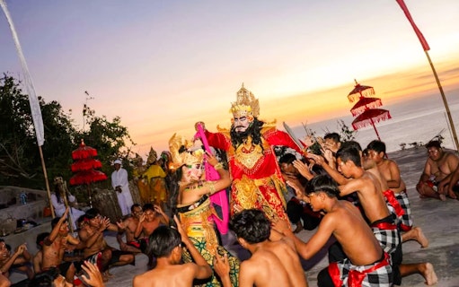 Kecak dance performance at Uluwatu Temple, Bali, with performers in traditional costumes at sunset.