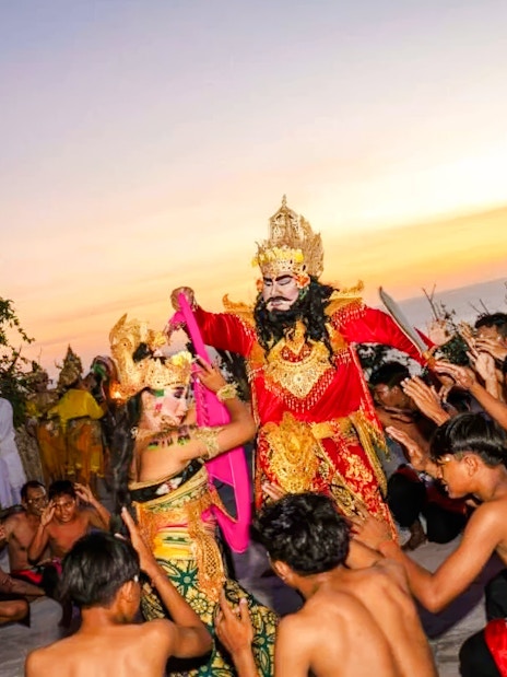 Kecak dance performance at Uluwatu Temple, Bali, with performers in traditional costumes at sunset.