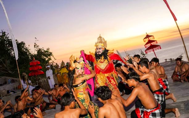 Kecak dance performance at Uluwatu Temple, Bali, with performers in traditional costumes at sunset.