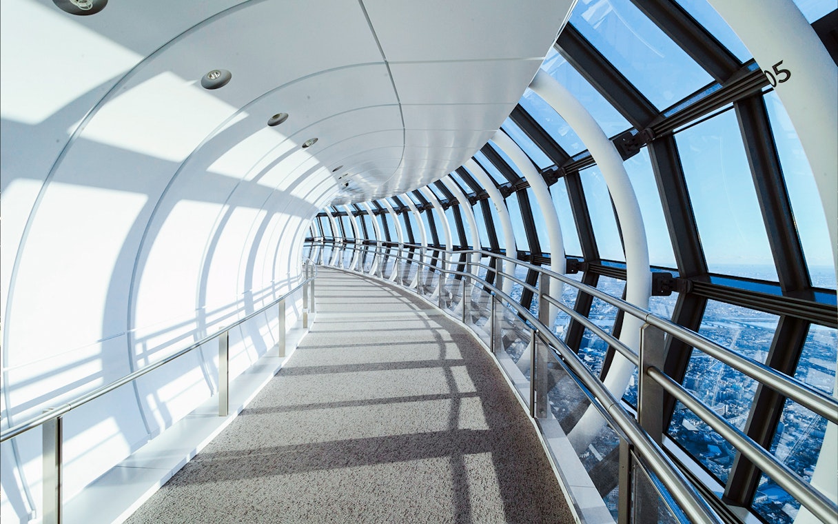 Curved glass corridor inside Tokyo Skytree with city view.