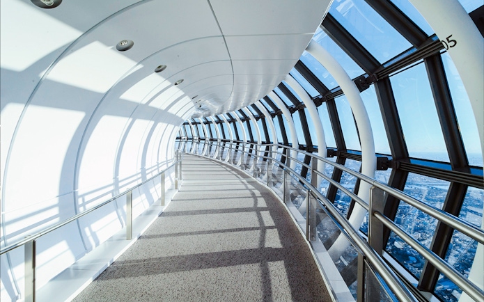 Curved glass corridor inside Tokyo Skytree with city view.