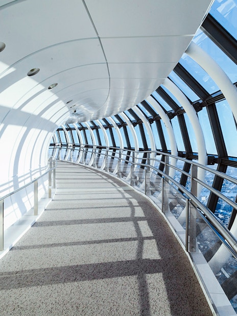 Curved glass corridor inside Tokyo Skytree with city view.