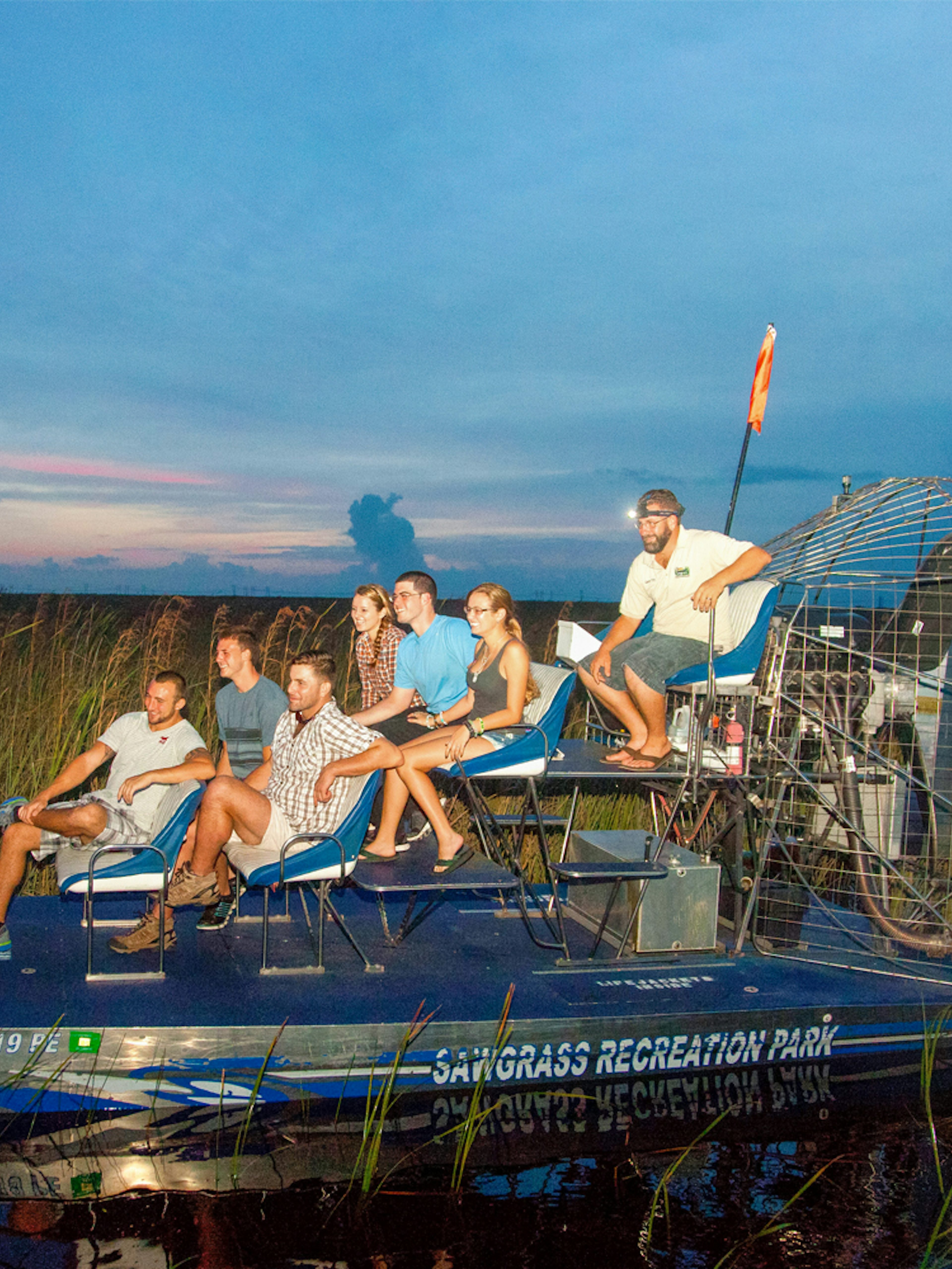 Group on an airboat during a night tour in the Everglades, surrounded by marshland.