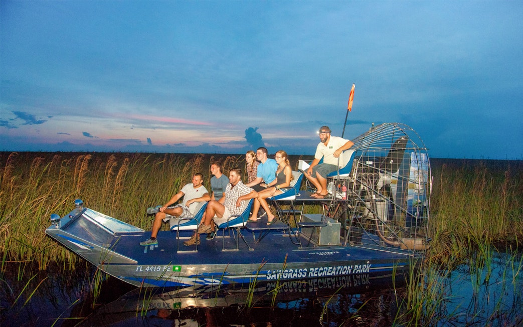 Group on an airboat during a night tour in the Everglades, surrounded by marshland.