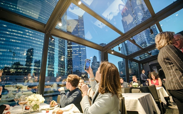 Dinner cruise guests enjoying Chicago skyline views through glass windows.