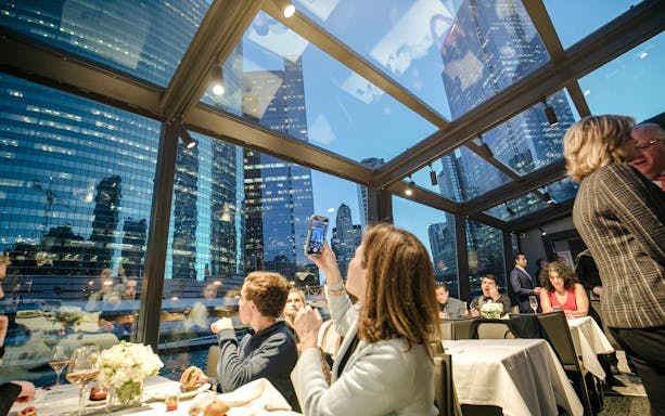 Dinner cruise guests enjoying Chicago skyline views through glass windows.