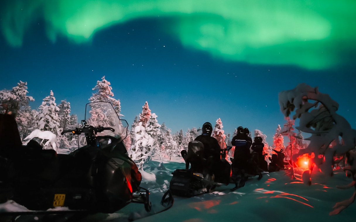 Snowmobile ride under Northern Lights in Levi, Finland.