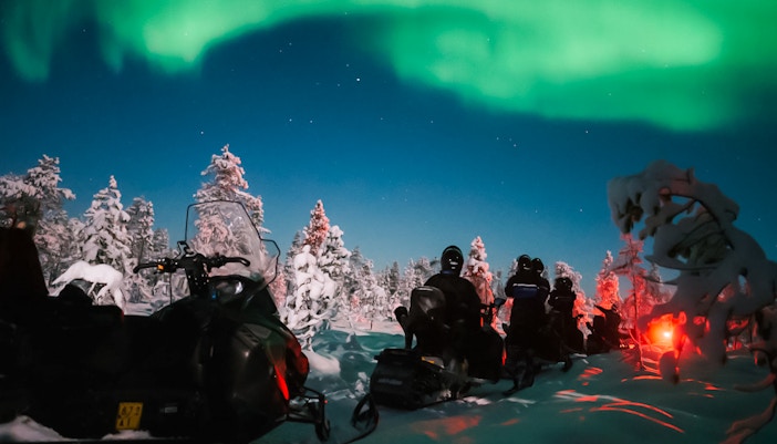 Snowmobile ride under Northern Lights in Levi, Finland.