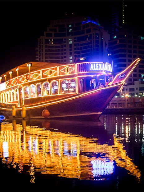 Alexandra VIP Dhow Cruise illuminated at night on Dubai Marina waters.