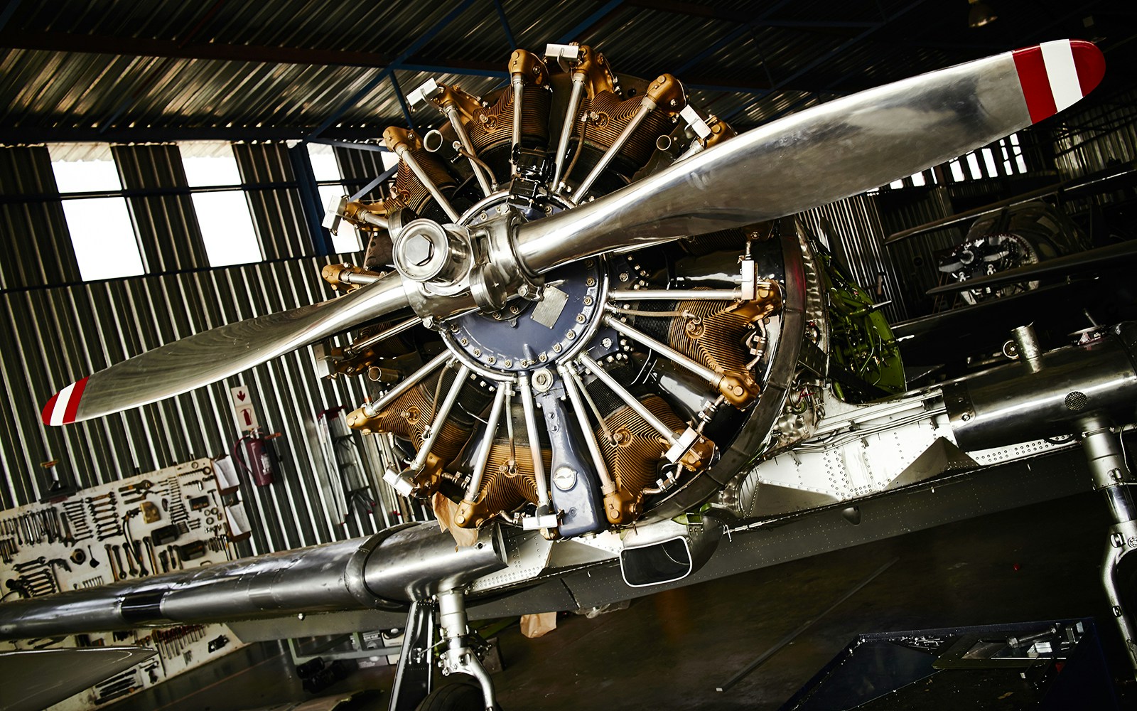 Old airplane propeller in a hangar with visible engine details.