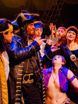 Pirates in costume holding a crown during the Pirates Dinner Adventure Show.