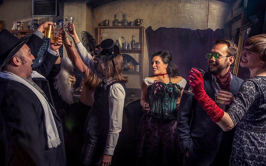 Visitors toasting drinks in a themed bar at London Dungeon.