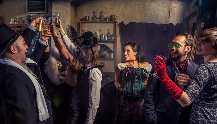 Visitors toasting drinks in a themed bar at London Dungeon.
