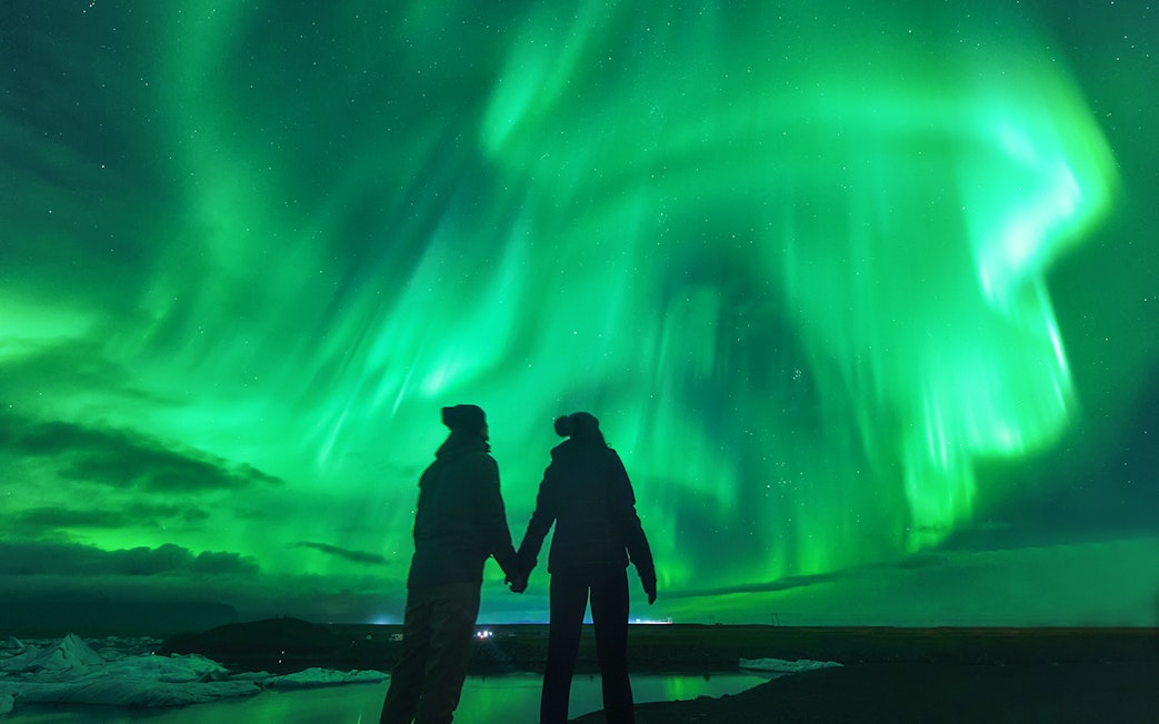 Tourists viewing Northern Lights in Iceland's night sky.